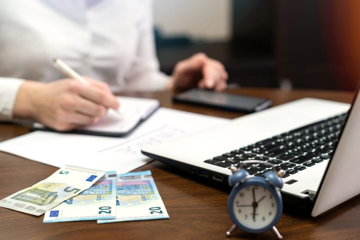 Woman working with finances on the table Woman working with finances on the table. Laptop, smartphone, money, notepad, clock
